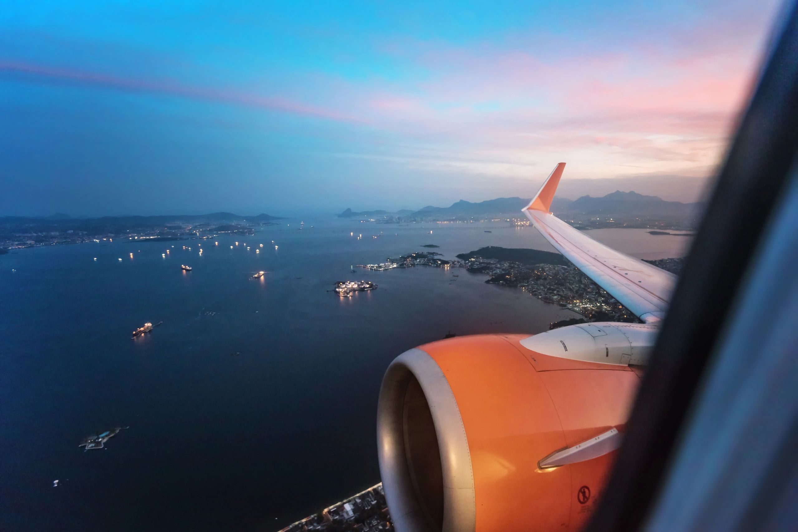 View from an airplane window over ocean at sunset